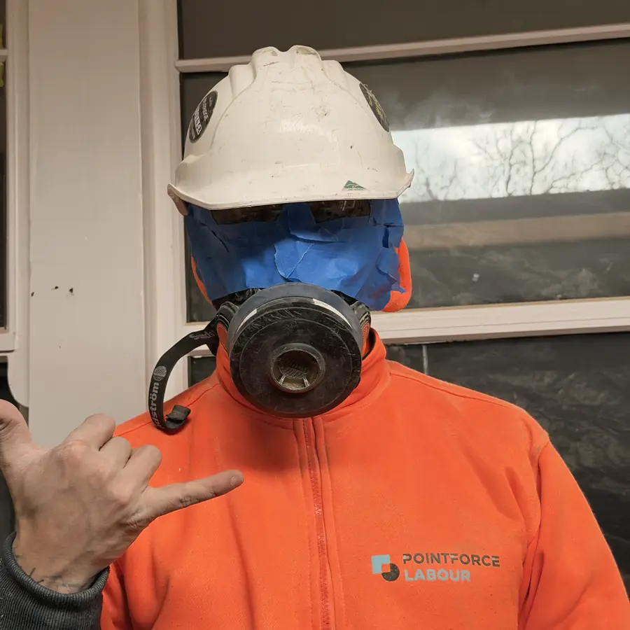 Helm, Schutzbrille und Atemschutzmaske über Arbeitskleidung