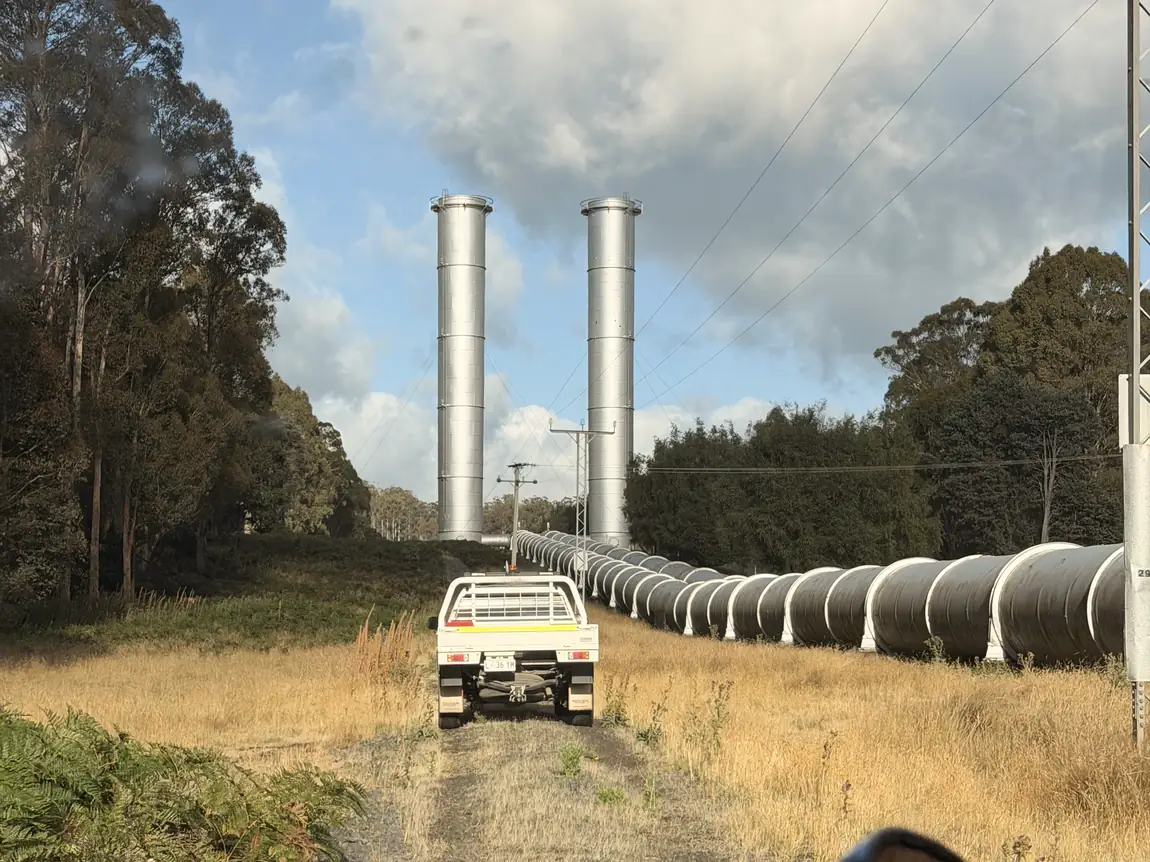 Blick aus einem Pick-up auf eine Pipeline entlang einer Schotterpiste